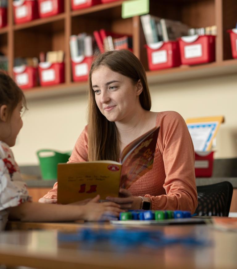 A teacher is reading to a young student