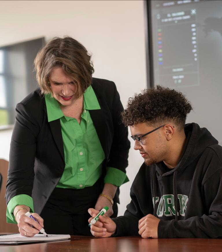 A cybersecurity professor helping a student in class.