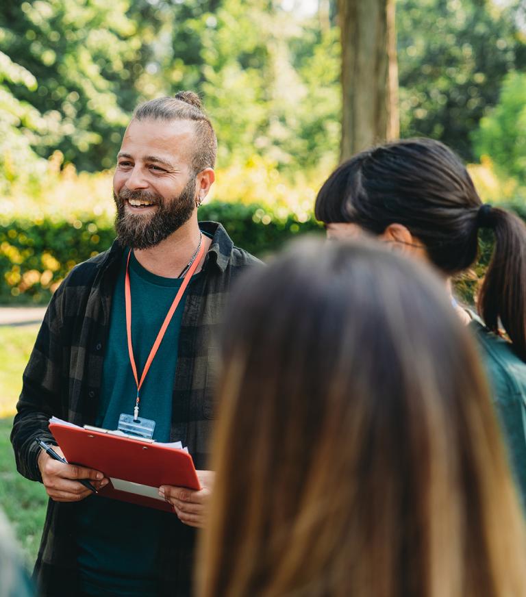 A student using a clipboard outside with a group.