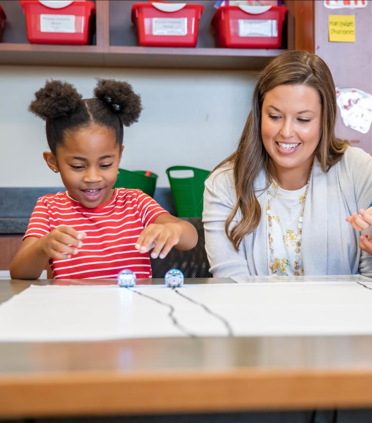 A student teacher working with 2 young students.