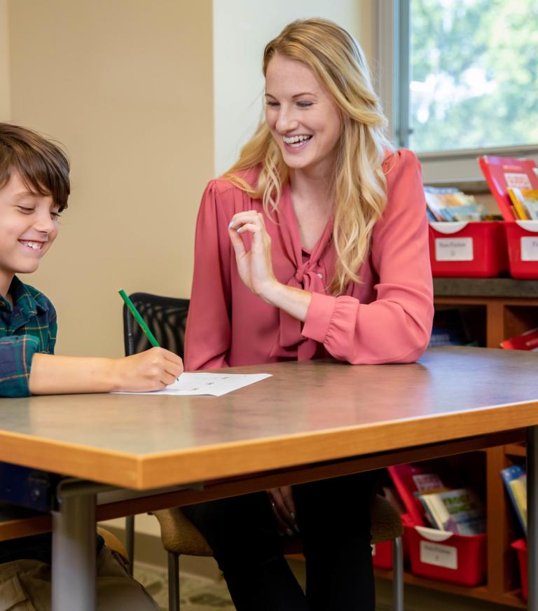 A teacher is helping a young student with their assignment