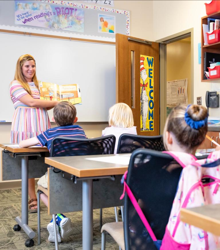 A student teaching four students in a classroom.