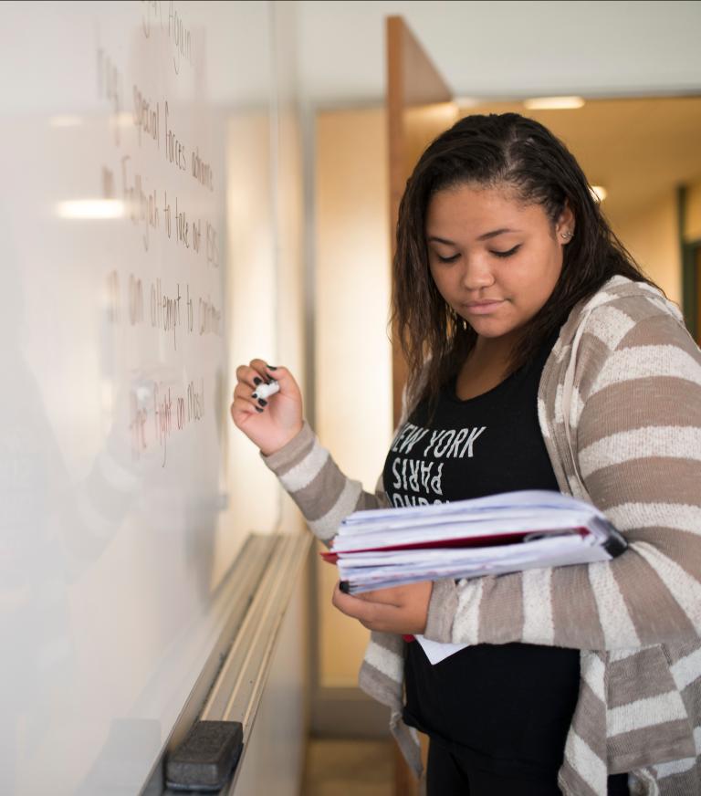 A student writing notes on a whiteboard.