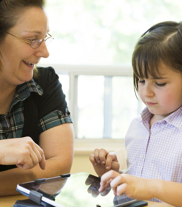 A teacher is teaching a young student with an Ipad