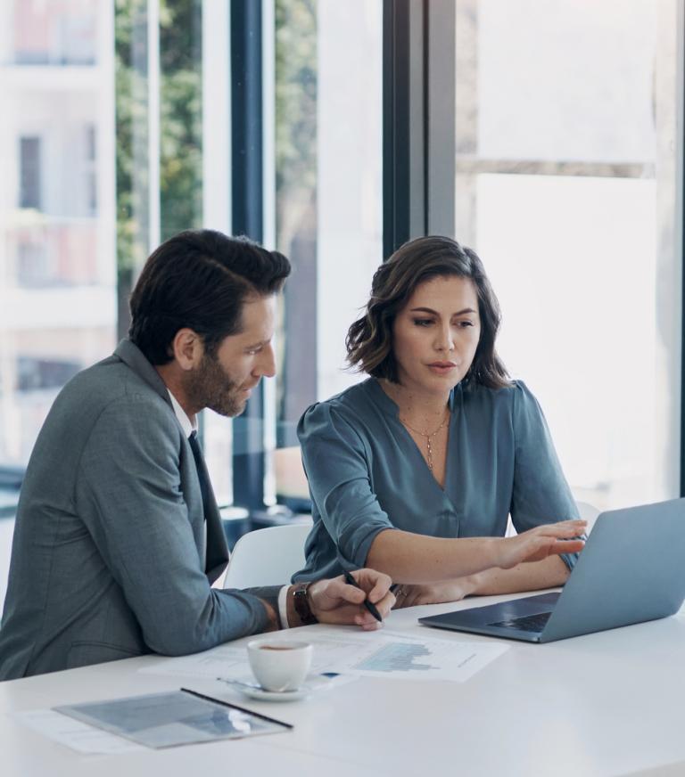 Two business people working at a desk with a lapton.