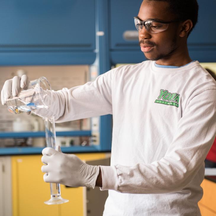 Chemistry student pours liquid into beaker in a laboratory