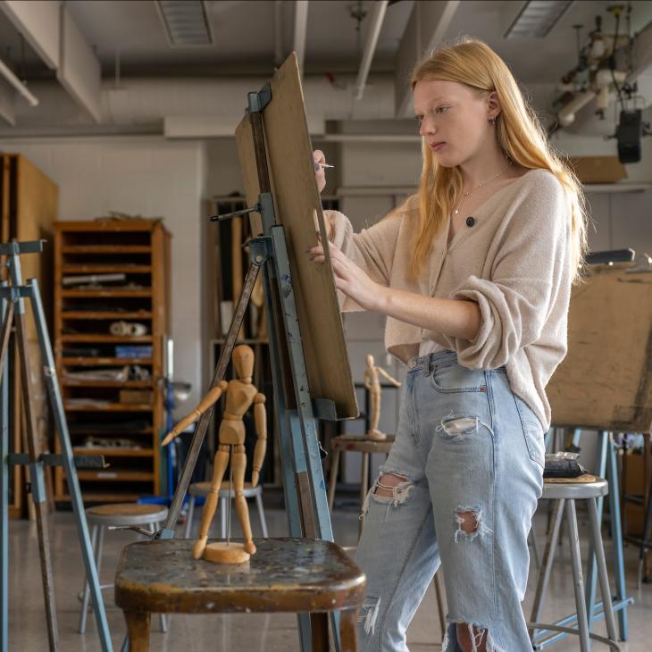 A student drawing on a canvas.