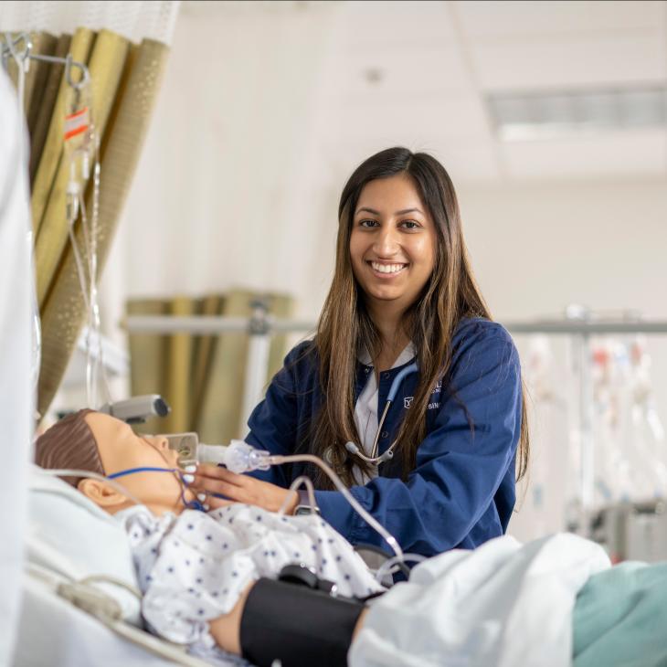 A nursing student practicing how to insert a ventilator on a patient.