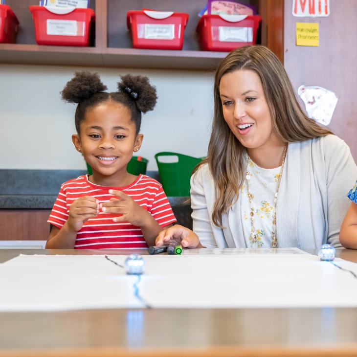 A teacher helping a student doing a craft.