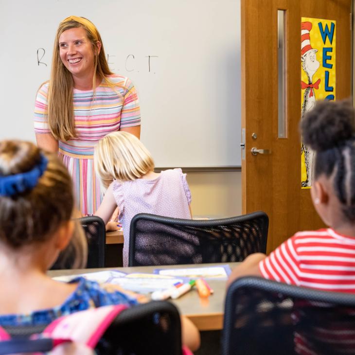 A graduate teacher is teaching a lesson to young students