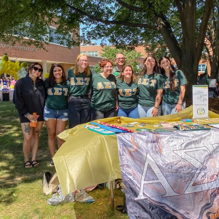 A group of students gather with Dr. Burns behind a table of sorority items for this photo