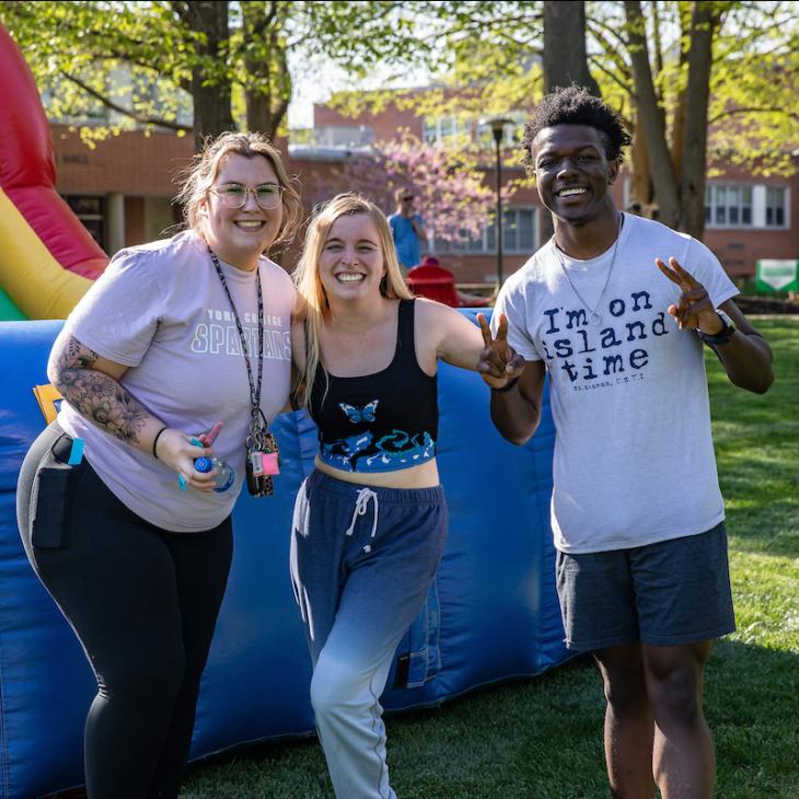 3 students at a CAB event smiling at the camera.