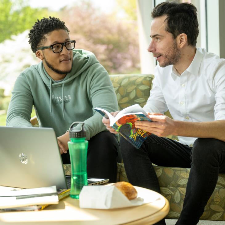 A professor is helping a student with class materials 