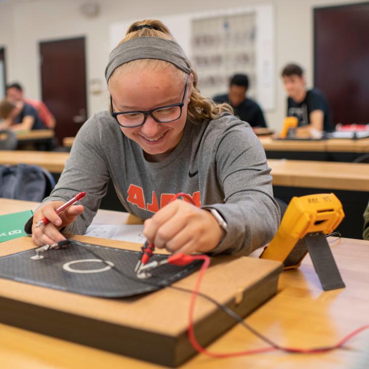 A student works with circuitry and wiring in the engineering lab.