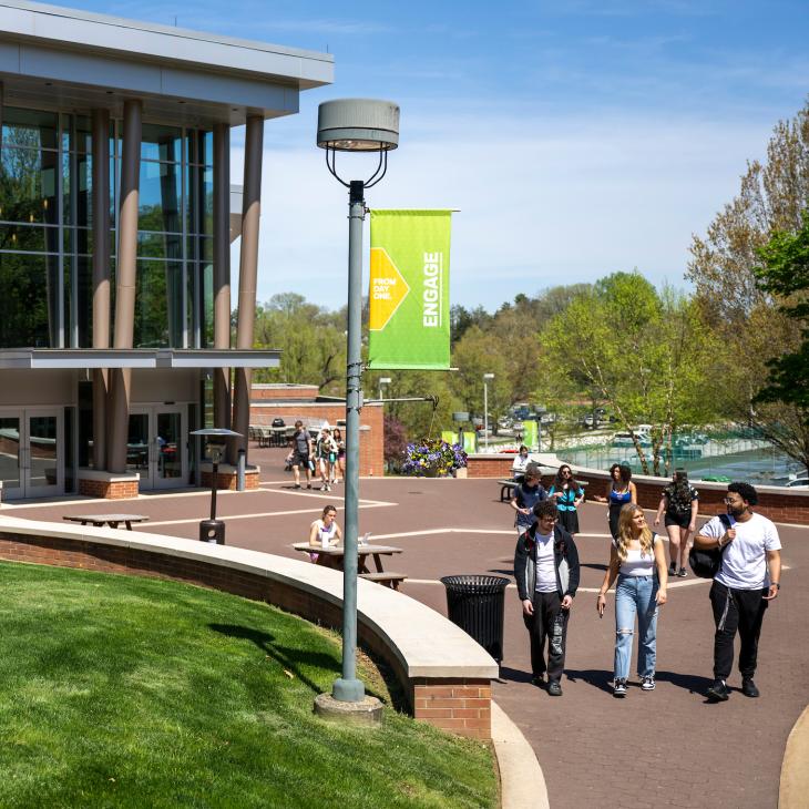 An exterior view of the Waldner Performing Arts Center's ornate glass front. A group of students walks along the sidewalk in front of the building.