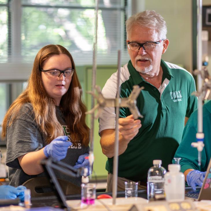 A chemisty professor conducting a lab experiment with two students in the chemistry lab.