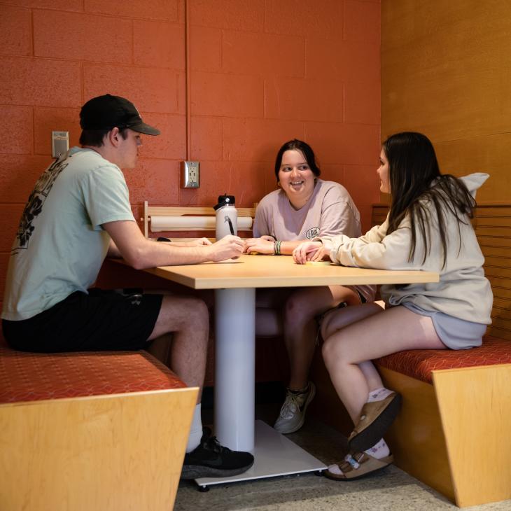 Three Honors Community students sitting at a table in the Graham Innovation Zone classroom.