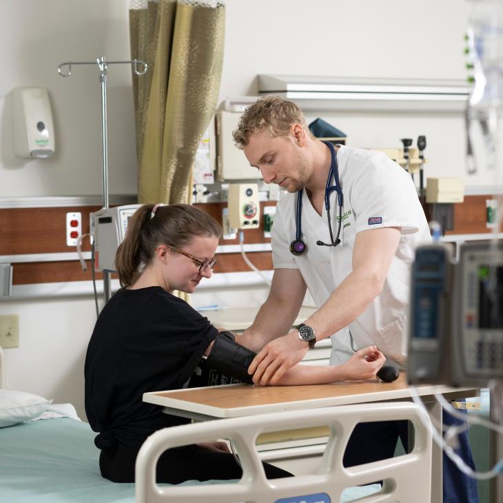 Two nursing students pracitcing their skills in the nursing lab.