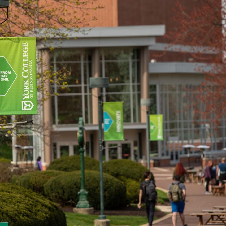 Walkway with pole banners and picnic tables leading to Waldner Performing Arts Center.