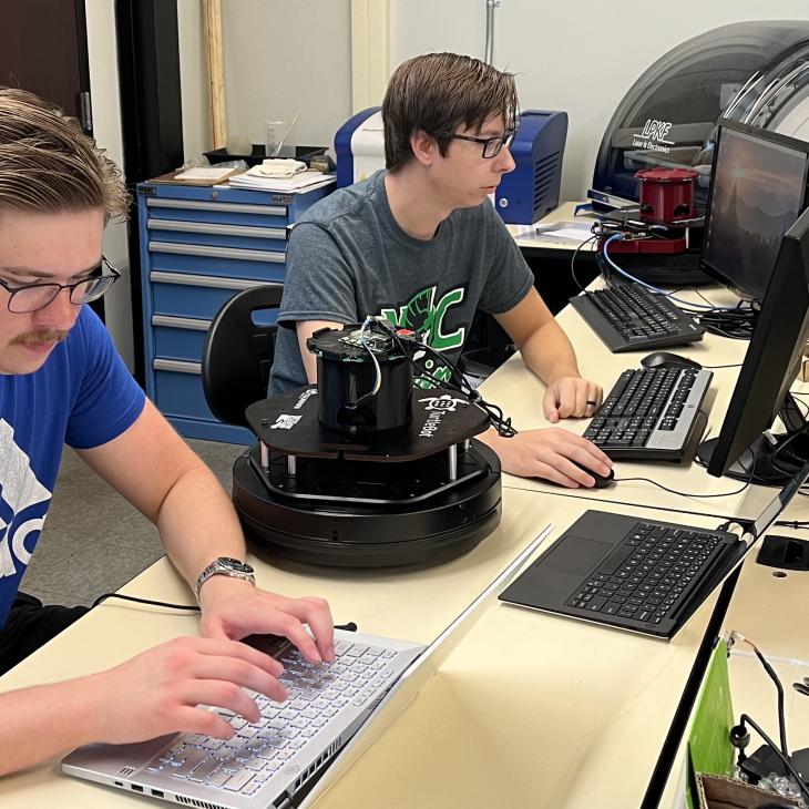 Two male students typing on computers in a lab