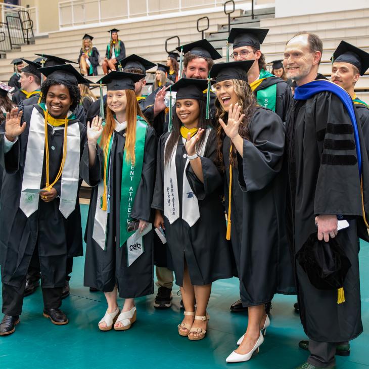 A group of students stands with their Professor at graduation