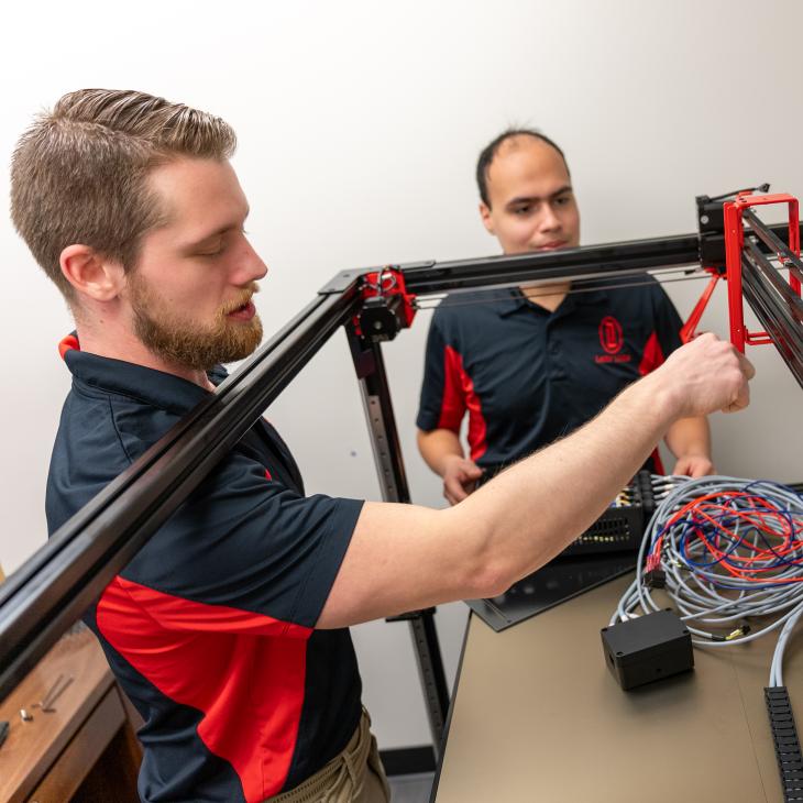 Two students work together on a technical structure