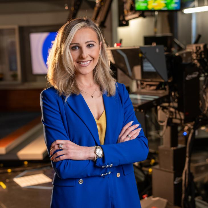 Alumna Grace Grill stands smiling in the Baltimore CBS station
