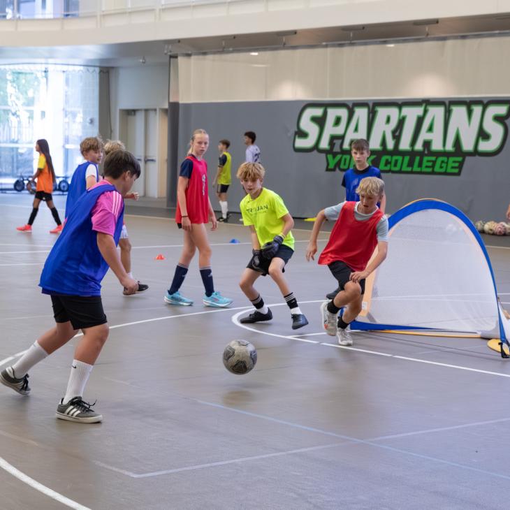 A group of students play soccer in the gym