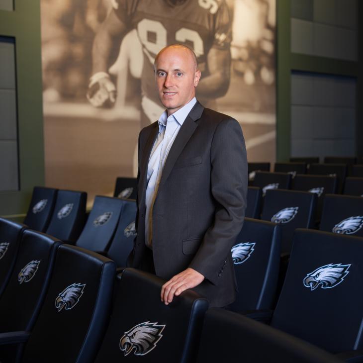 Bryce Johnston stands in a theater with the Philadelphia Eagles logo surrounding him