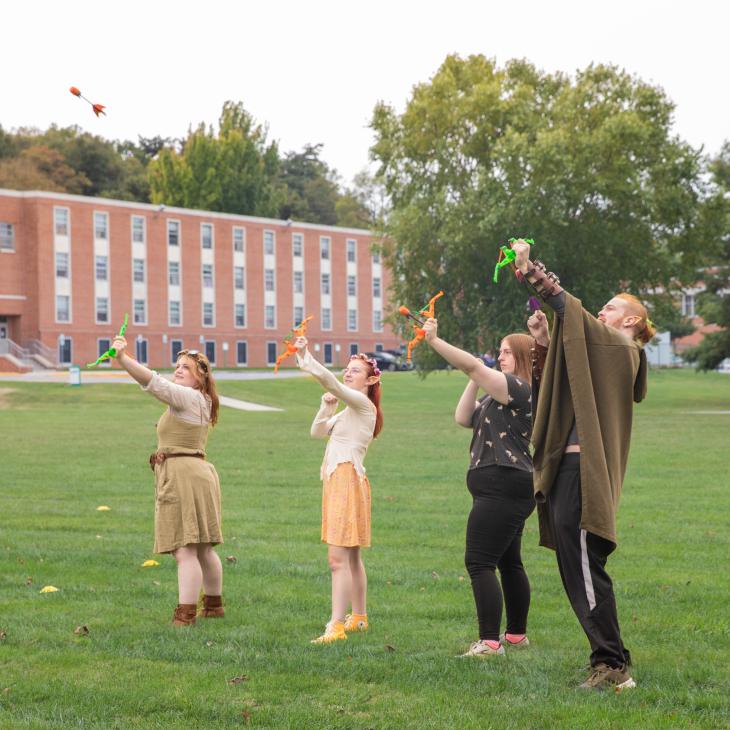 A group of LARPers aiming false bows and arrows in the air.