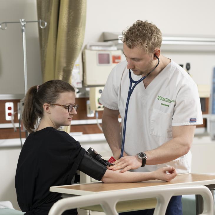 Second degree nursing student at York College takes blood pressure during a hands on nursing lab session