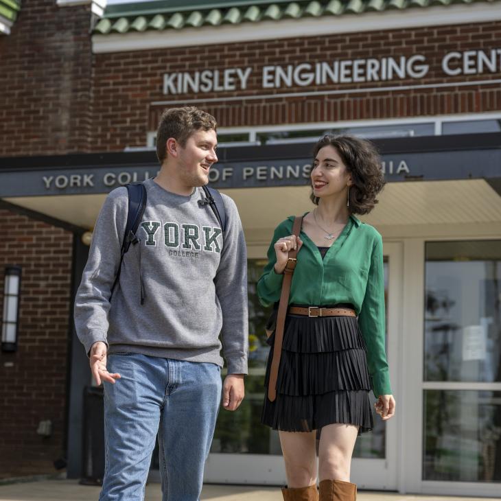 Two students walking together outside a brick building with the words Kinsley Engineering Center.
