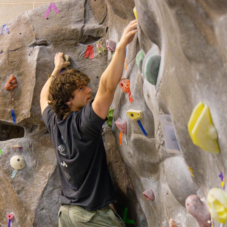 Rock climber perched on an indoor rock climbing wall.