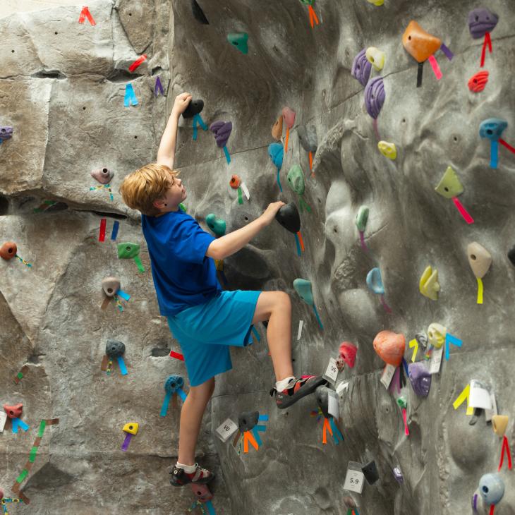A student climbs an indoor rock wall.