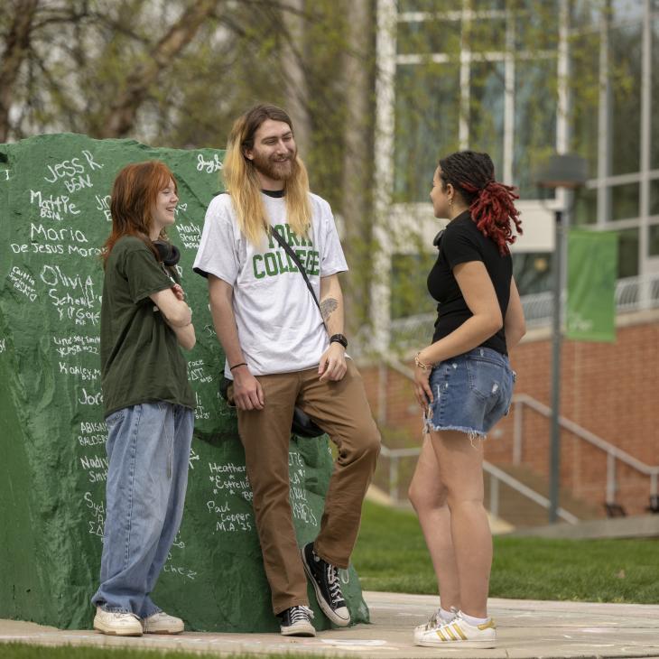 Three students standing together at the rock Spring 2026