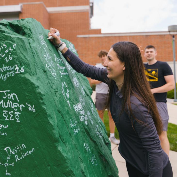 A student signs 'Ol Spart at commencement