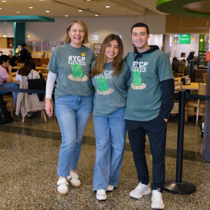 Three people wearing YCP Gives tshirts, standing in Johnson Dining Hall at York College of Pennsylvania